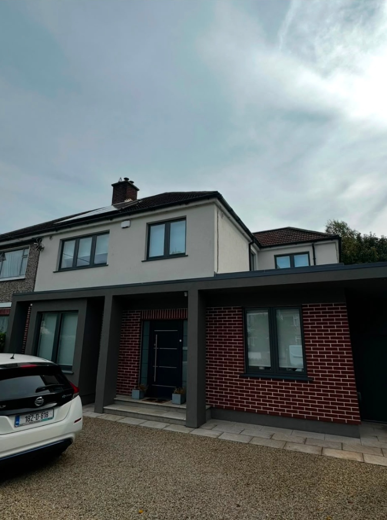 Finished house exterior with grey render extension and red brick facade